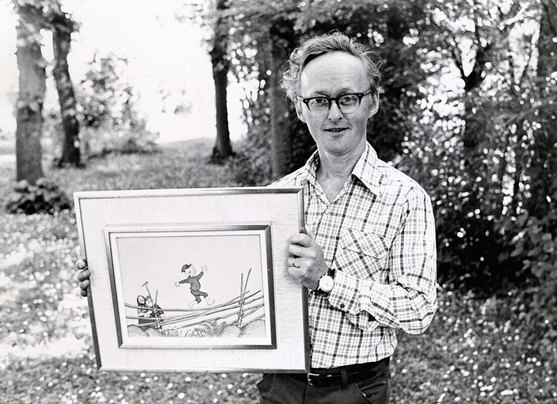 Björn Berg visar upp en inramad illustration av Emil i Lönneberga. Bilden är svartvit och tagen på 1970-talet.